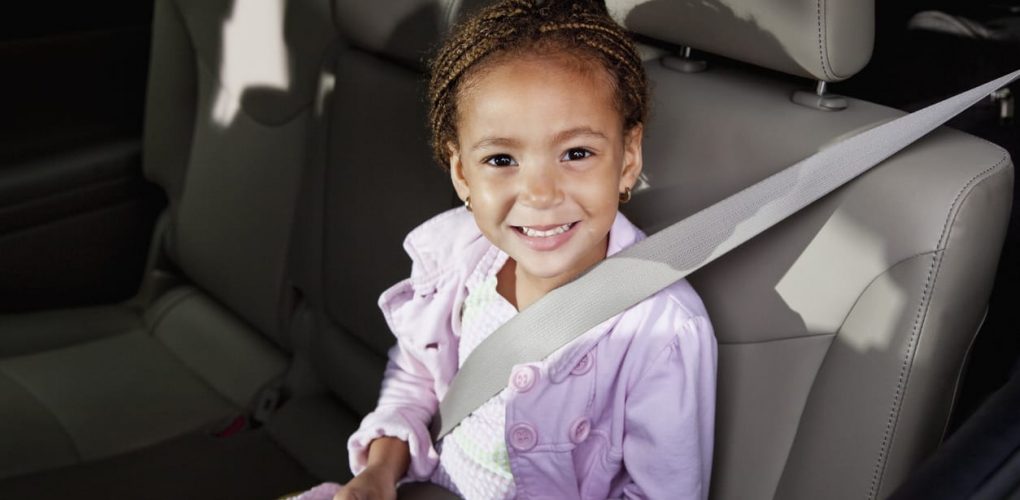 Little girl (4 years, mixed race African ethnicity), riding in car, wearing seat belt.